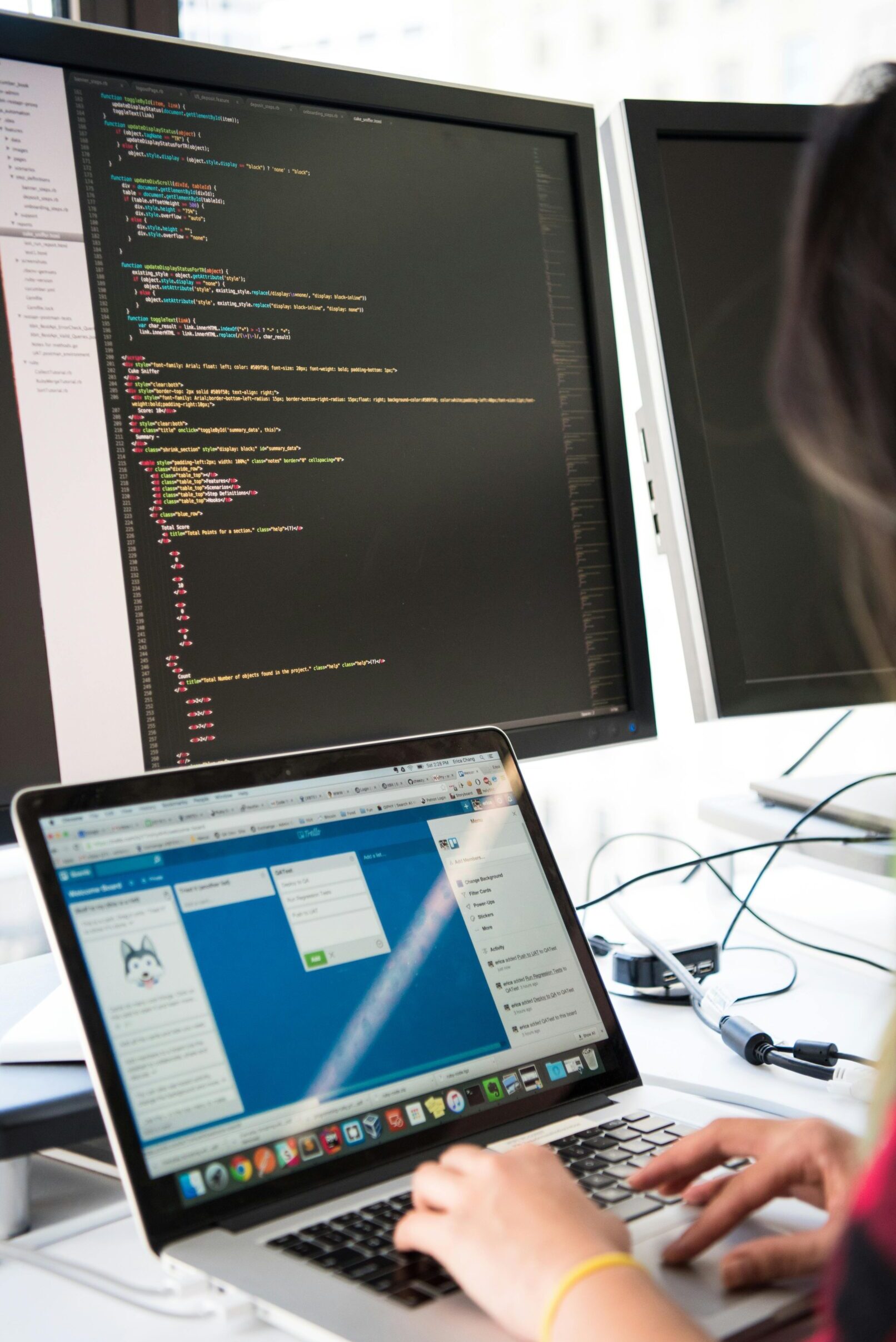 Programmer working on code across multiple screens in a modern office setting.